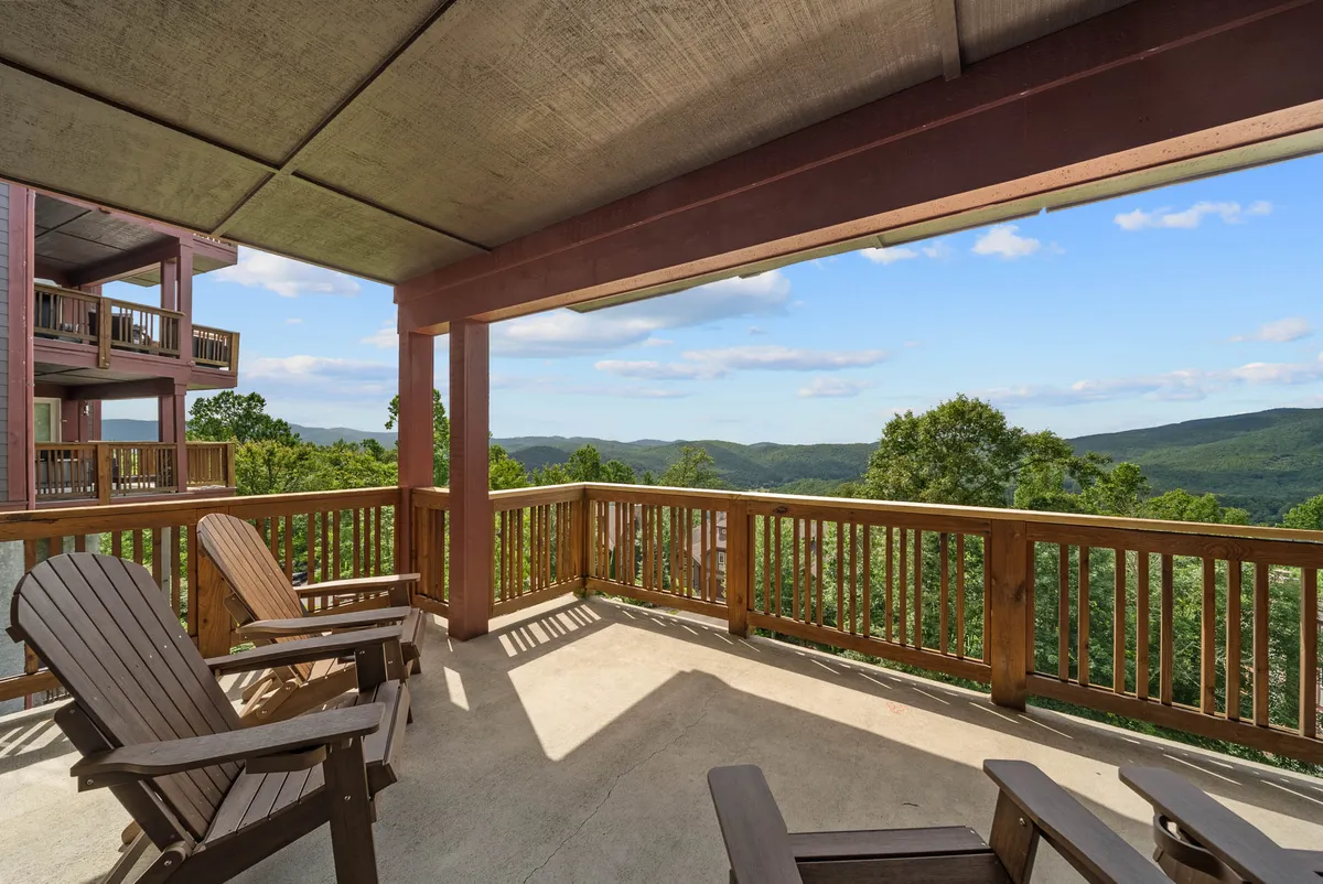 An inviting exterior shot of the wooden deck furnished with Adirondack chairs, offering a panoramic mountain view. The scene evokes the tranquility of sipping coffee at sunrise or toasting sunset, just steps from the heart of the retreat.