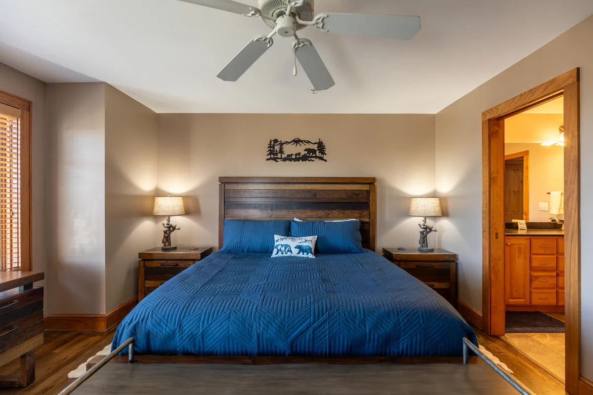 A spacious bedroom featuring a large bed flanked by elegant nightstands, soft lighting from bedside lamps, and tasteful decorative wall art. The neutral color palette and uncluttered furnishings create a serene and inviting atmosphere, ideal for relaxation and peaceful sleep.